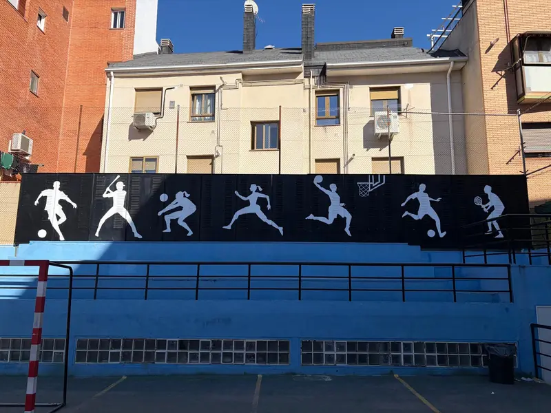Muro de la pista con siluetas de deportistas: fútbol, béisbol, voleibol, baloncesto y tenis