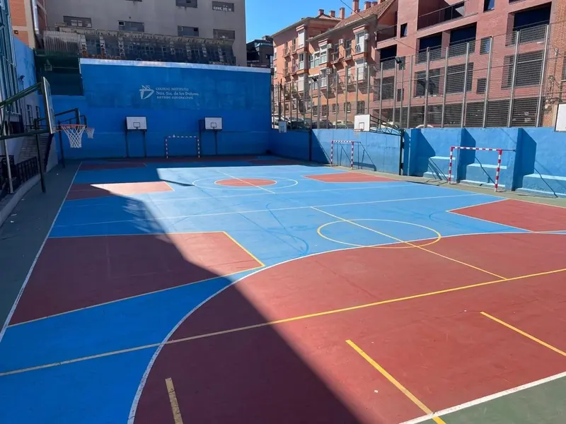 Pista deportiva del colegio, con las canastas y el escudo pintado en la pared